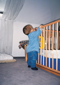 Kleinkind - Kleinkind steht an einem Bett Kleinkind - Kleinkind steht an einem Bett